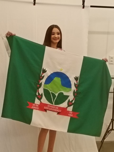Ayla segura a bandeira de Divino de São Lourenço durante apresentação oficial.