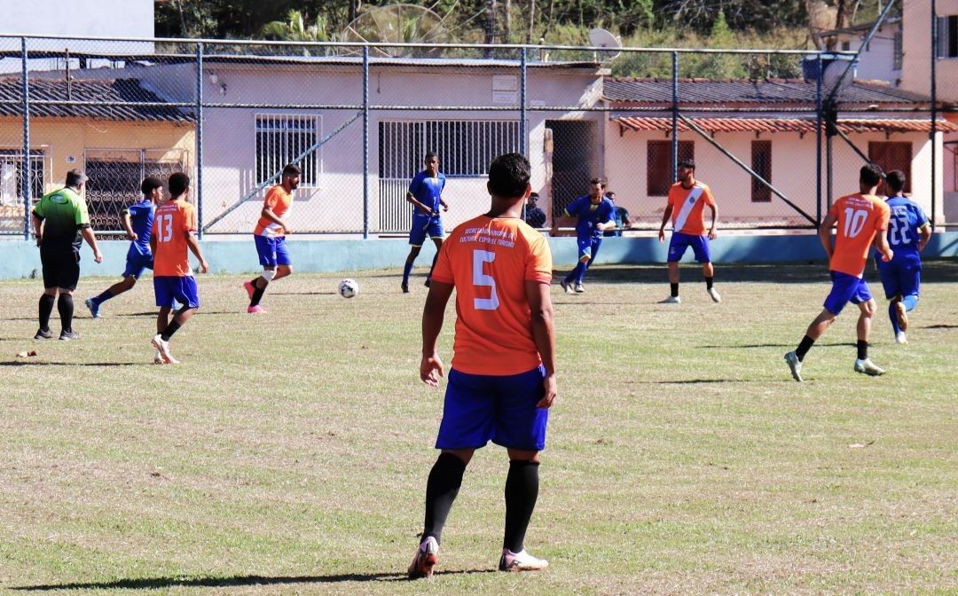 Jovens atletas disputam partida de futebol de base em campo gramado durante competição esportiva em Dores do Rio Preto.