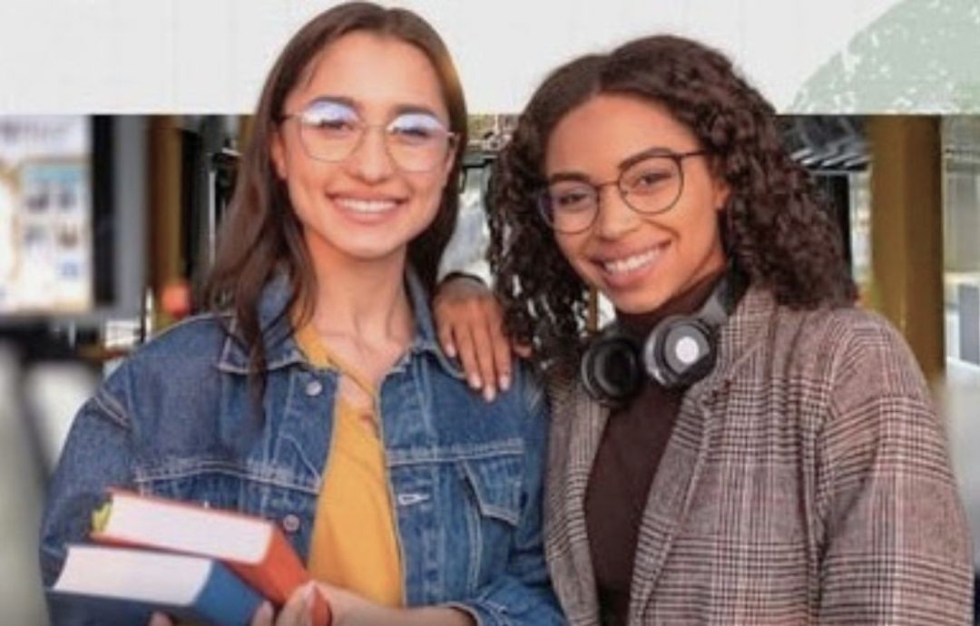 Estudantes sorrindo, segurando livros e materiais acadêmicos, representando jovens beneficiados por programas de apoio estudantil.