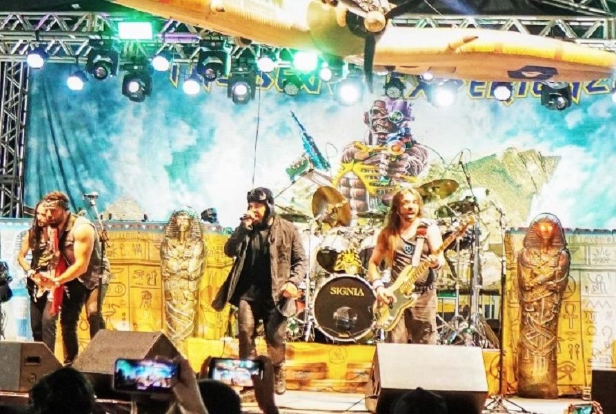 Banda de rock se apresentando no palco principal do Iúna Motofest, com estrutura cenográfica temática, iluminação profissional e grande interação com o público.