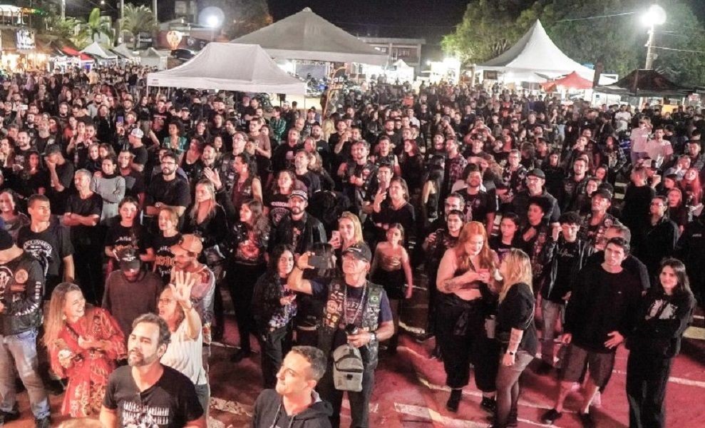 Público reunido no Parque de Exposições de Iúna durante o Iúna Motofest, com grande concentração de motociclistas, visitantes e barracas iluminadas à noite.