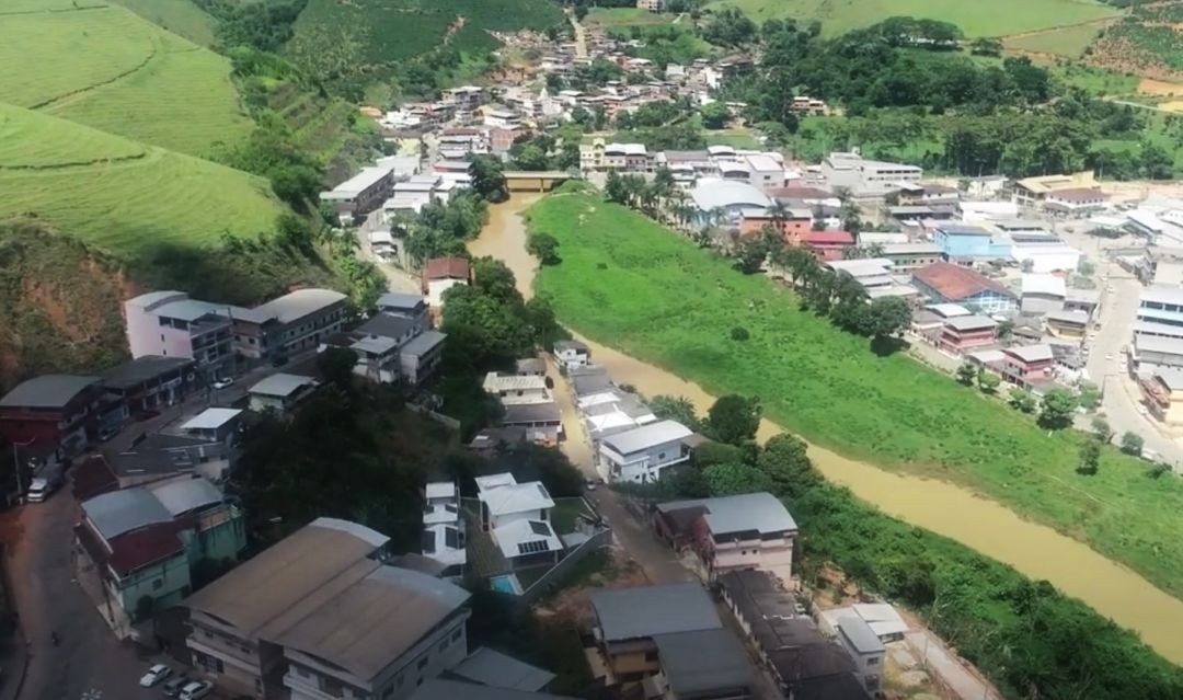 Vista aérea do município de Ibitirama, com área urbana cortada por um rio e cercada por vegetação verde, representando o município que conquistou o Selo Ouro Nacional em Alfabetização.