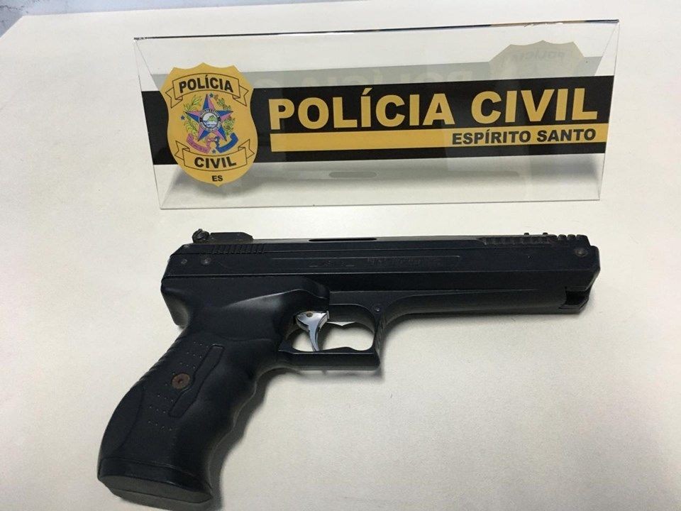 Simulacro de pistola apreendido pela Polícia Civil do Espírito Santo exibido sobre mesa com identificação da corporação ao fundo.