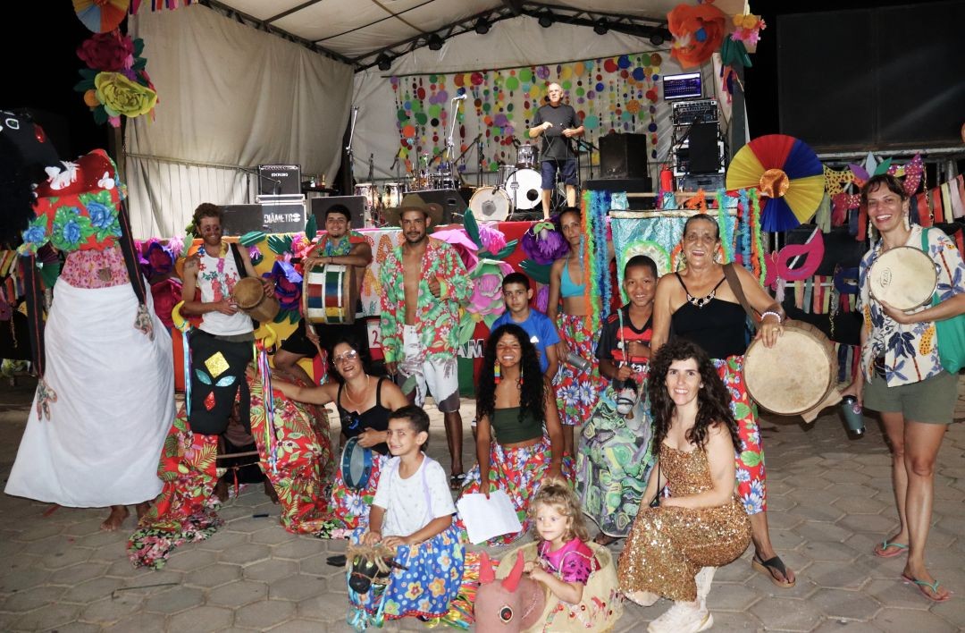 Participantes do Bloco do Boi se reúnem em frente ao palco decorado, com fantasias coloridas, tambores e personagens da cultura popular, incluindo representação do boi e elementos tradicionais, durante o Carnaval 2026 em Patrimônio da Penha.