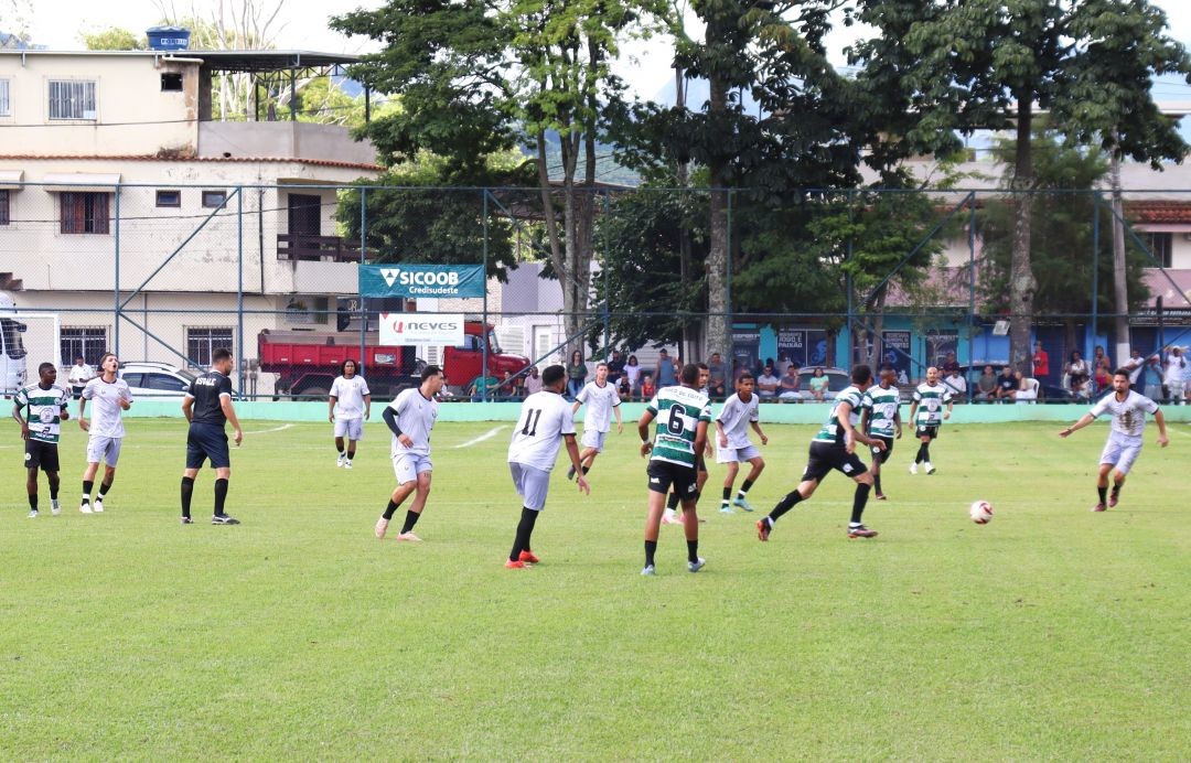 Lance da partida entre Santa Clara e Agroserra pela rodada de abertura do 1º Campeonato Sicoob Credisudeste, com jogadores disputando a bola no meio de campo e público ao fundo nas arquibancadas.
