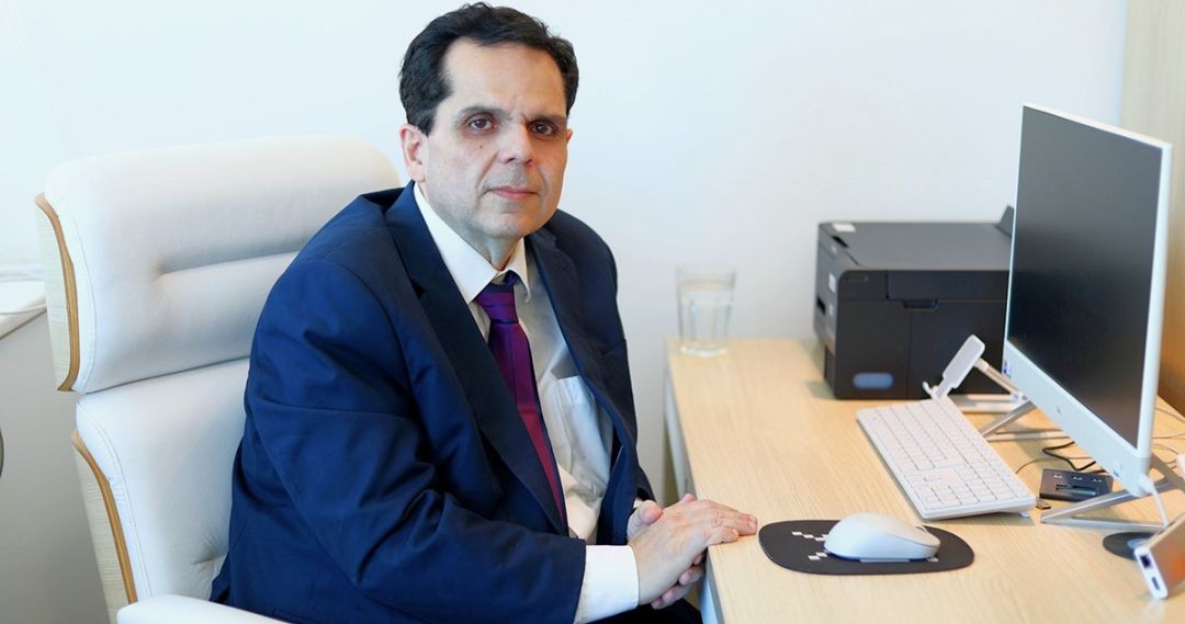 Advogado eleitoral Marcelo Nunes sentado em escritório, usando terno azul e gravata, em frente a um computador, imagem usada para ilustrar explicações sobre a janela partidária.