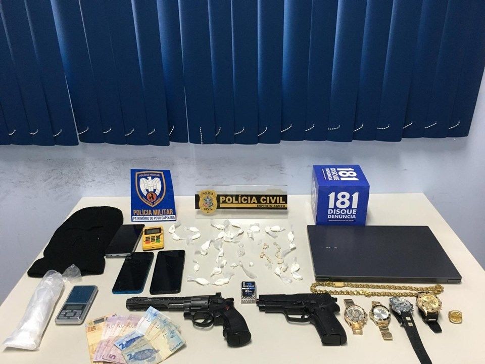 Mesa com drogas apreendidas, armas simuladas, dinheiro, celulares e objetos recolhidos durante operação da Polícia Civil e Polícia Militar em Guaçuí, no Espírito Santo.