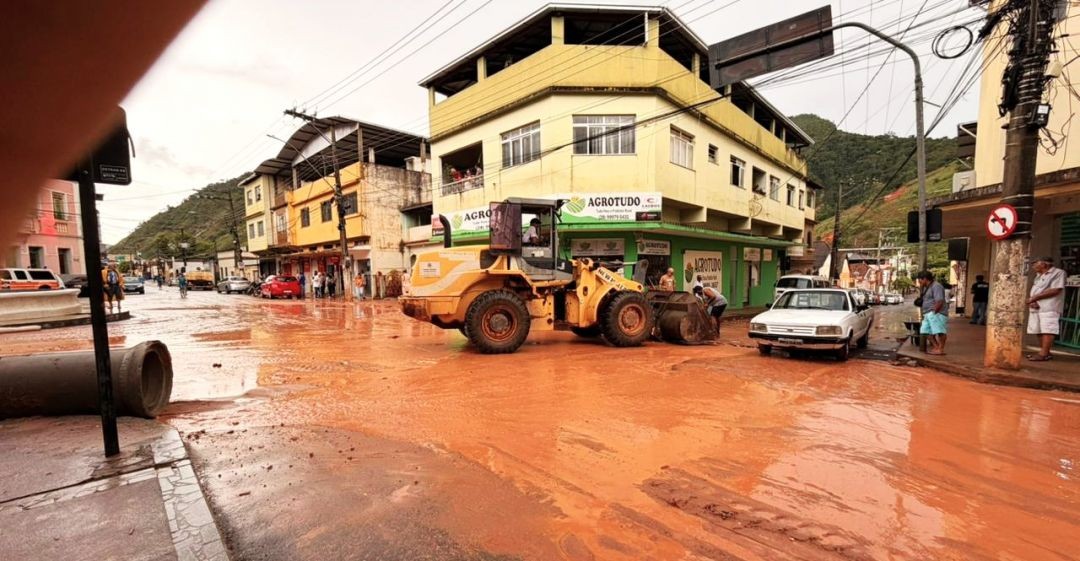 Máquina da prefeitura realiza limpeza de lama e resíduos em rua do Centro de Muniz Freire após alagamento provocado por chuva intensa.