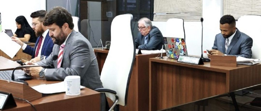 Na foto, quatro vereadores verificam informações sobre a denúncia apresentada contra o prefeito de Ibatiba, sentados em poltronas brancas, atrás de mesas de madeira.