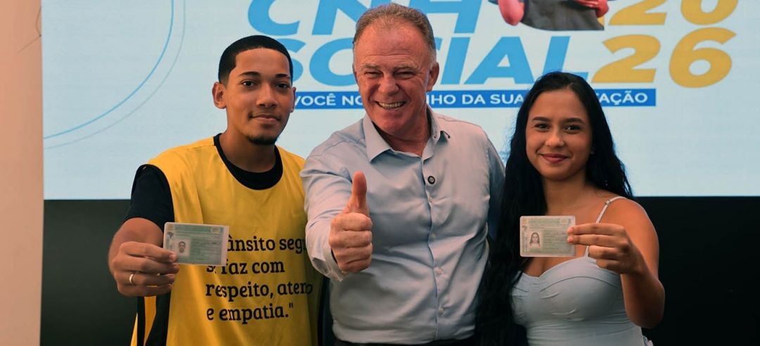 Governador ao centro posa ao lado de dois jovens beneficiários exibindo suas carteiras de habilitação durante o lançamento do CNH Social 2026.