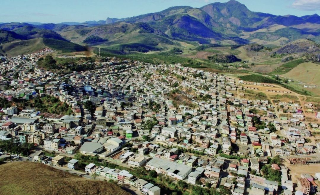 Vista aérea do município de Iúna, no Espírito Santo, com área urbana ao centro e montanhas ao fundo, com destaque para o Pico Colossus.