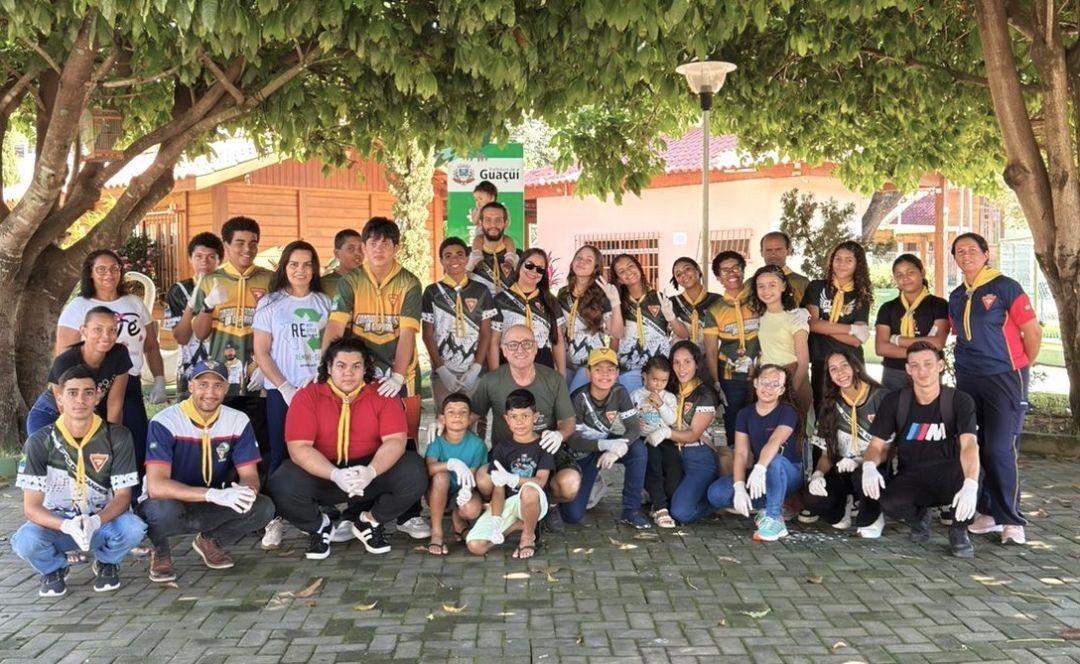 Grupo de participantes posa reunido em praça após atividade ambiental, incluindo crianças, adolescentes e adultos.