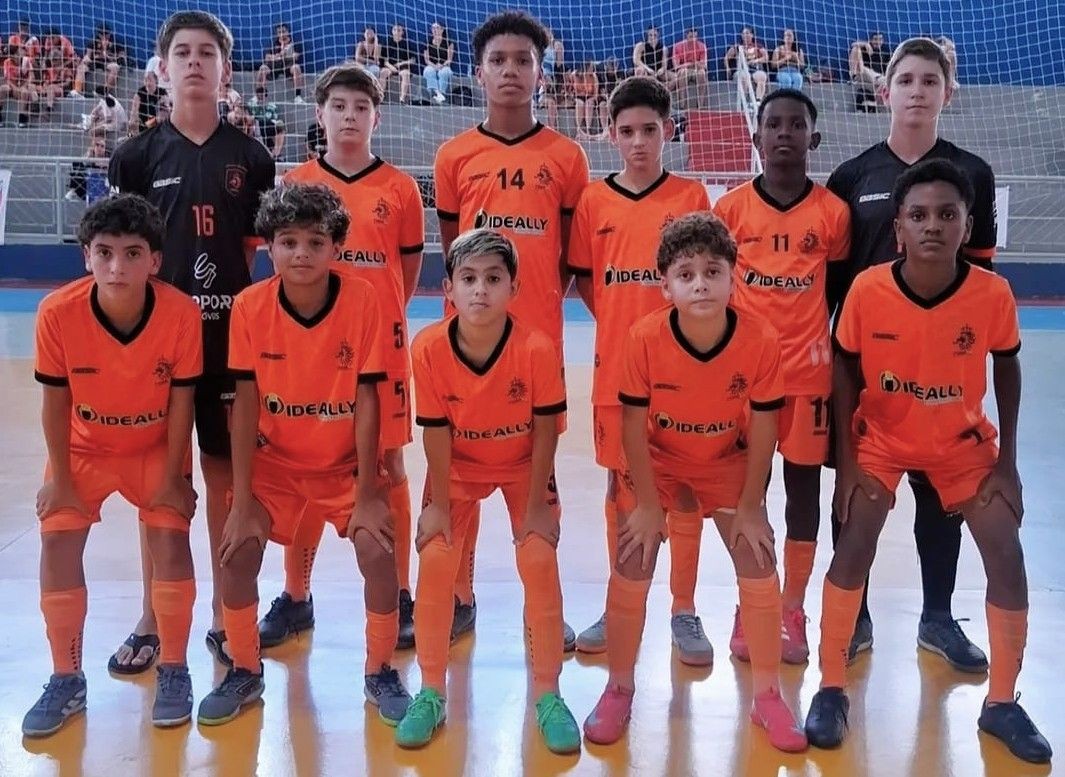Jogadores da equipe do CT Porto, posando para foto oficial em quadra, vestindo uniforme laranja com detalhes pretos.