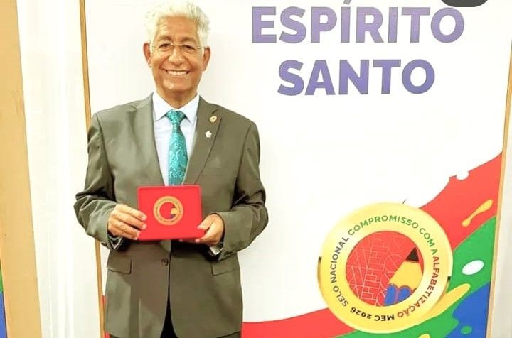 O prefeito Luis Pancoti, de terno cinza e gravata azul, segura o estojo com a medalha de ouro do MEC. Ao fundo, o logotipo oficial do Selo Nacional Compromisso com a Alfabetização 2025.
