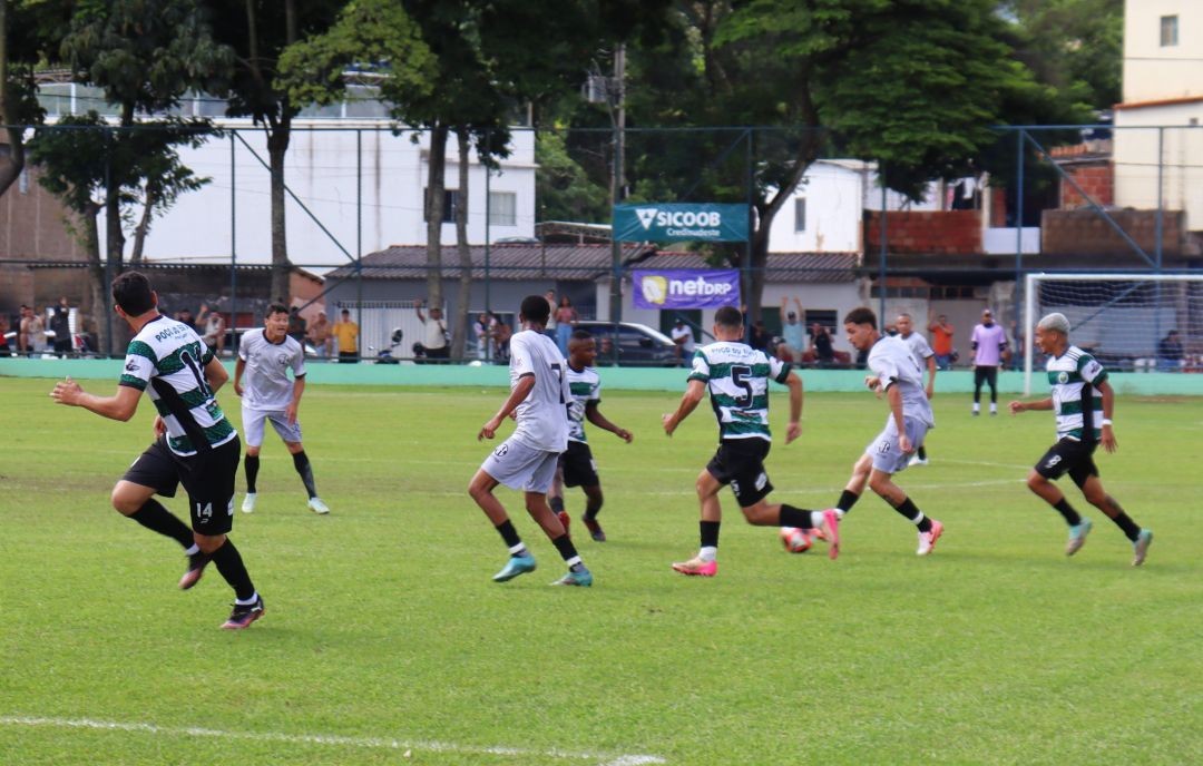 Jogadores disputam lance durante partida do Campeonato Regional de Futebol de Campo em Dores do Rio Preto, com equipes em campo e torcedores ao fundo no estádio municipal.