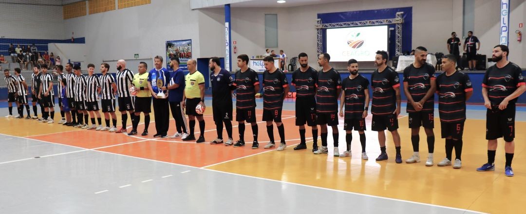 Equipes do Resenha e Oncell perfiladas, tendo ao centro autoridades e arbitragem, no meio da quadra do Ginásio Poliesportivo de Iúna, na abertura da final da Copa Helpnet Telecom de Futsal 2026.