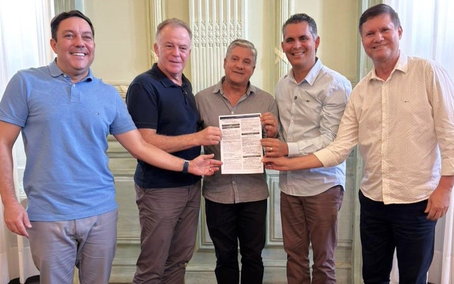 Bruno Lamas, Renato Casagrande, Romário Vieira, Gilson Daniel e Dary Pagung posam para foto segurando a publicação do edital tendo ao fundo parede de cor clara.