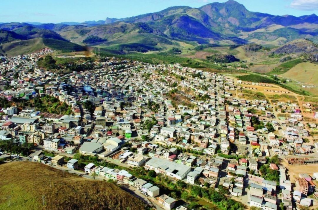 Vista aérea da cidade de Iúna, no Espírito Santo, destacando área urbana cercada por montanhas.
