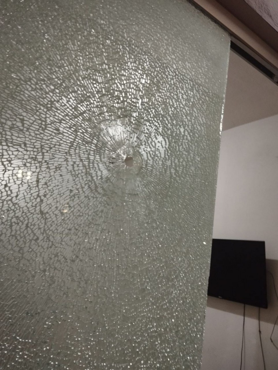 Marca de disparo em vidro de bar onde duas pessoas foram baleadas durante confusão.