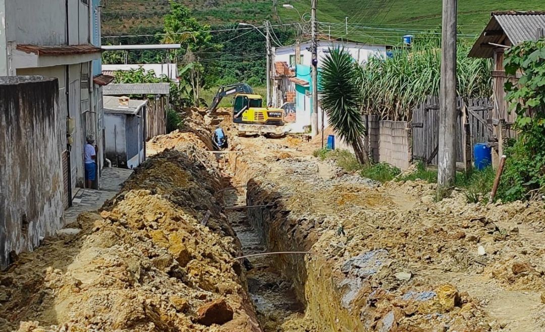 Escavação de vala em rua de Mundo Novo para instalação de rede de drenagem, com máquina e trabalhadores no local.
