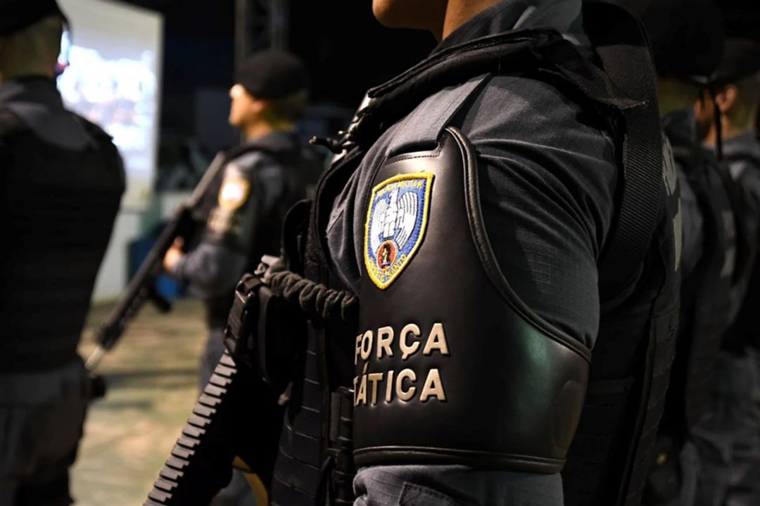Policiais da Força Tática da Polícia Militar do Espírito Santo, em formação, durante operação noturna, equipados com coletes e armamento, em ação de segurança pública.