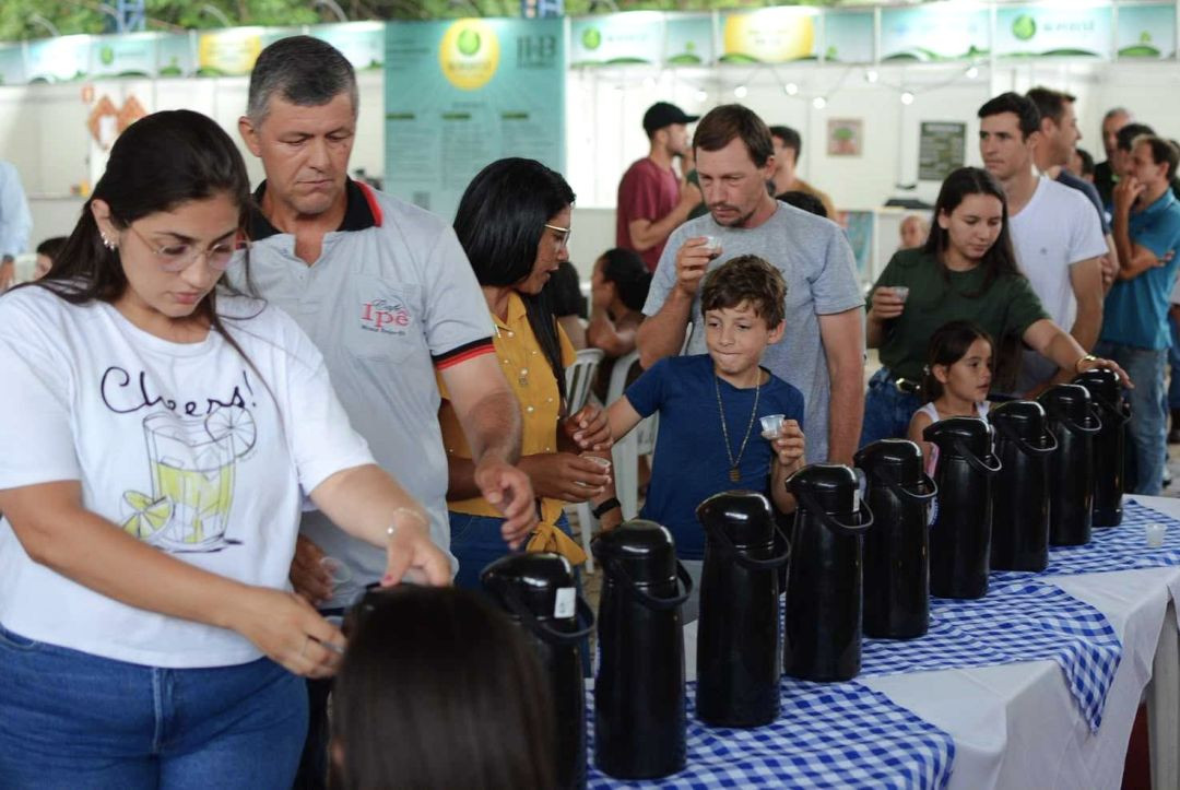 Participantes realizam degustação de cafés especiais durante evento em Muniz Freire, em frente a uma mesa com garrafas térmicas utilizadas para servir as amostras do concurso.