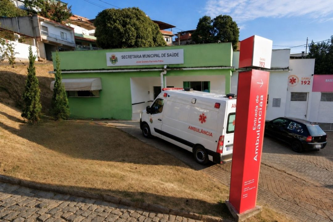 Prédio da Secretaria Municipal de Saúde de Dores do Rio Preto, com uma ambulância do SAMU estacionada em frente à entrada.